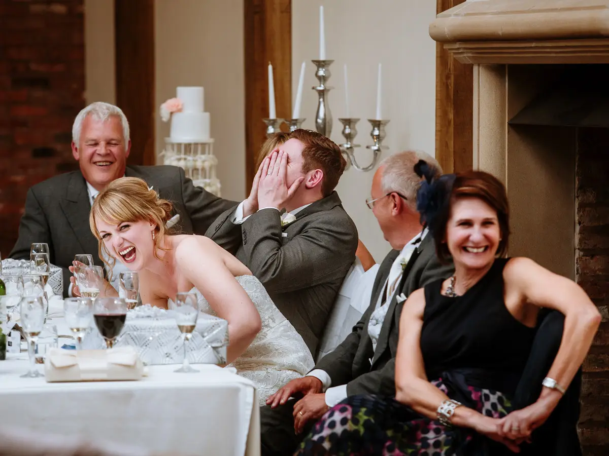 Bride laughs during speeches while groom hides his face — Gary Phillip documentary wedding photography