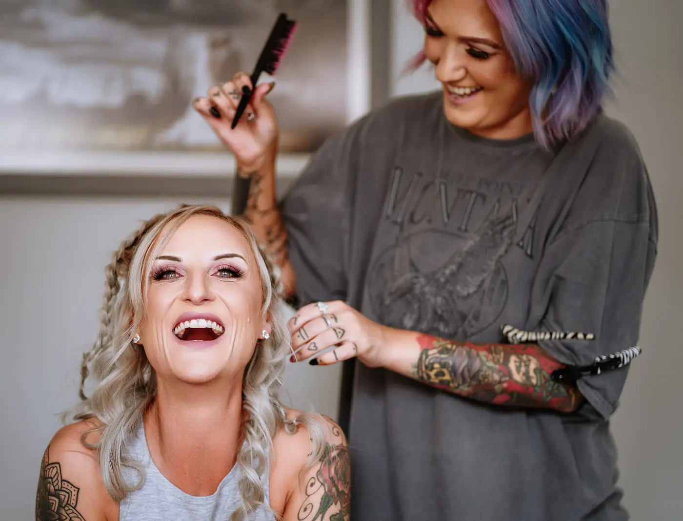 Bride Amy laughing while her hair is being styled during wedding morning preparations at Doddington Hall, Lincolnshire