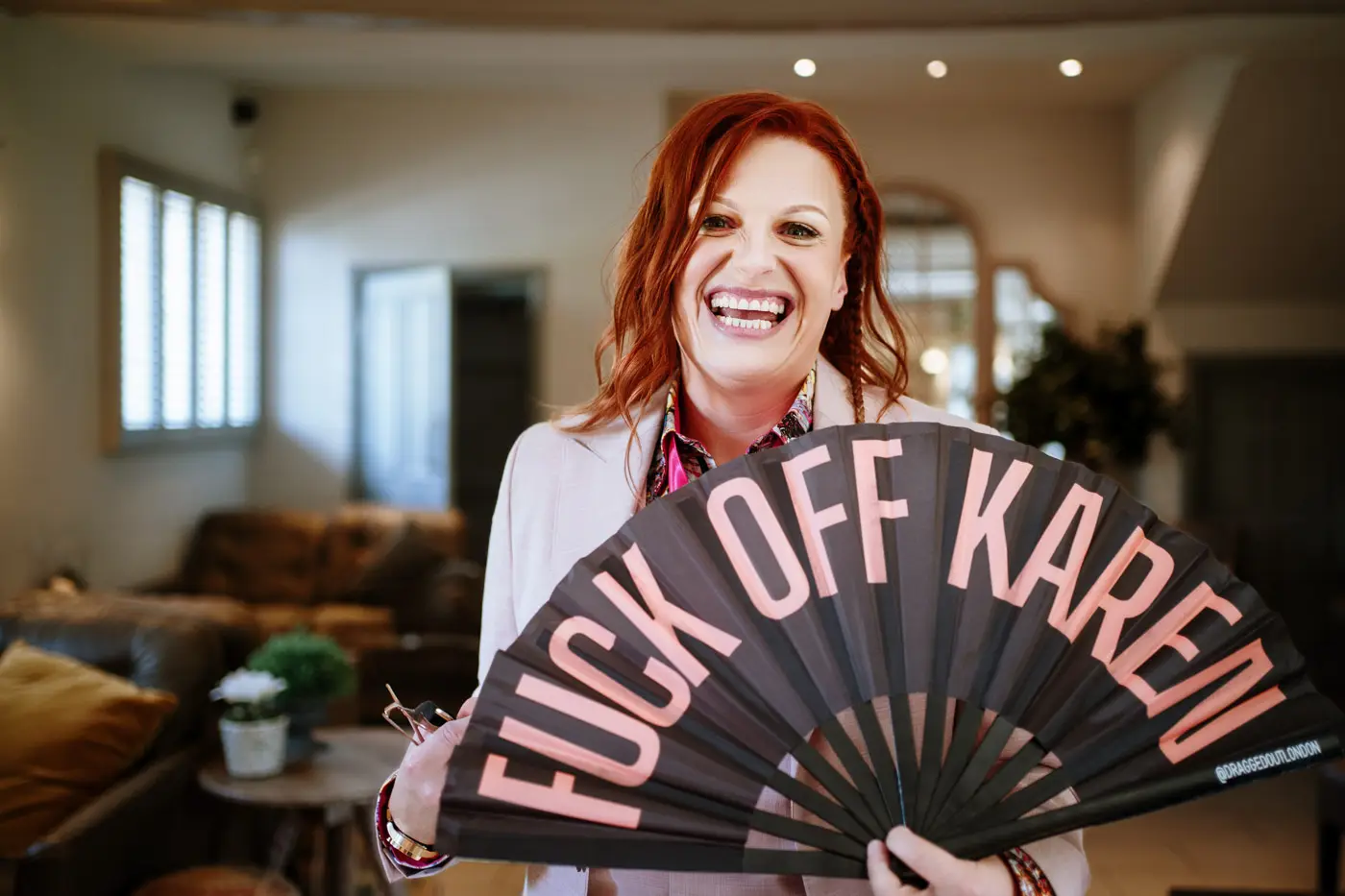 Abby with a massive smile holding a large decorative fan at Doddington Hall, Lincolnshire on her wedding day