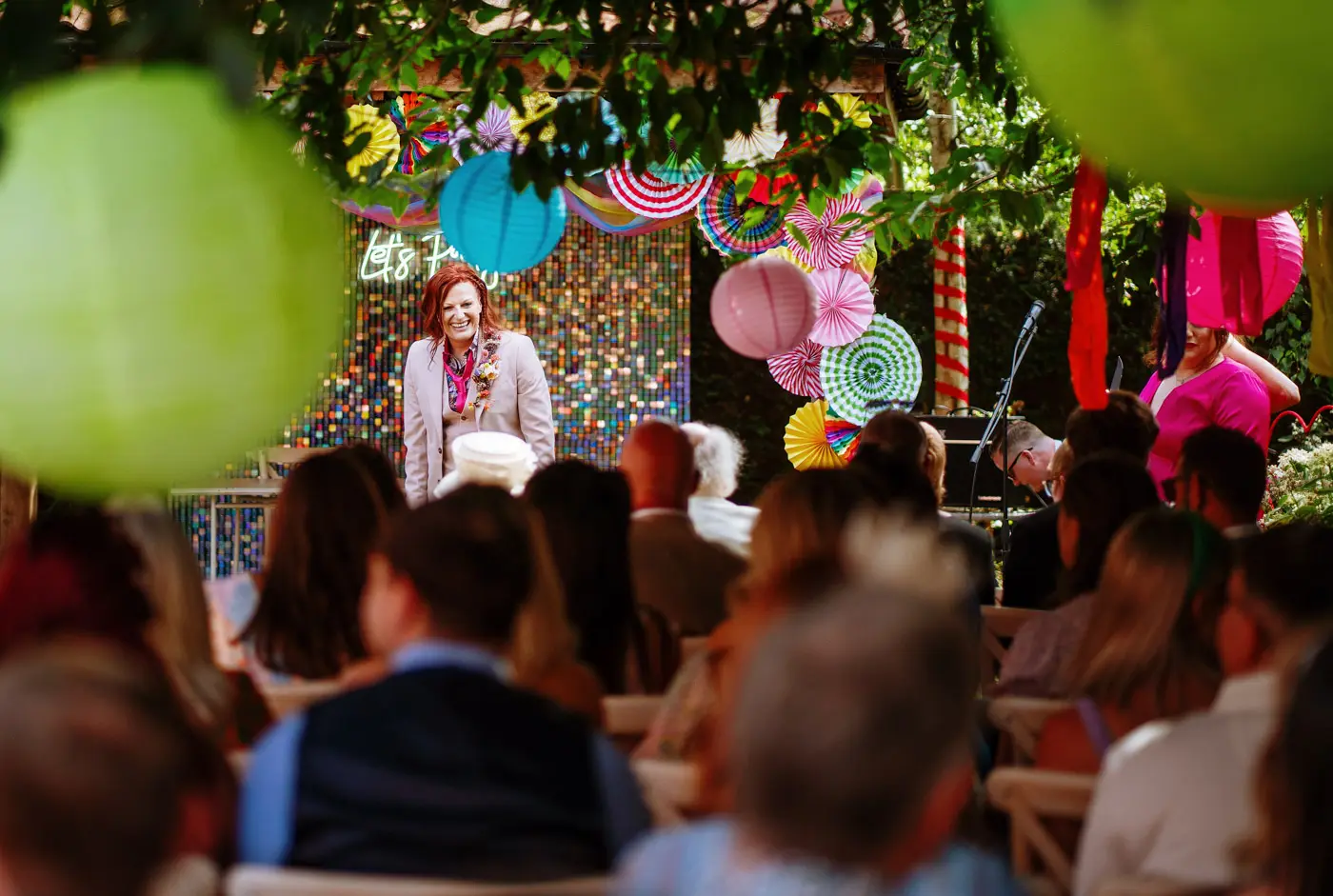 Abby waiting at the front of the ceremony room seen through all of the seated guests at Doddington Hall, Lincolnshire