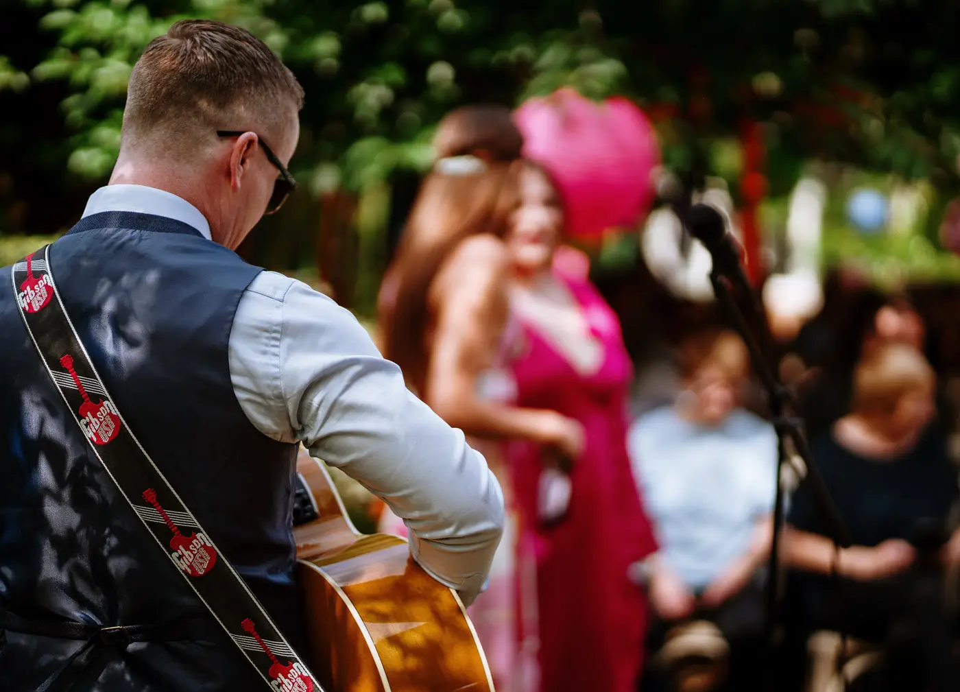 A musician playing guitar and singing to entertain guests before Amy and Abby's wedding ceremony at Doddington Hall, Lincolnshire