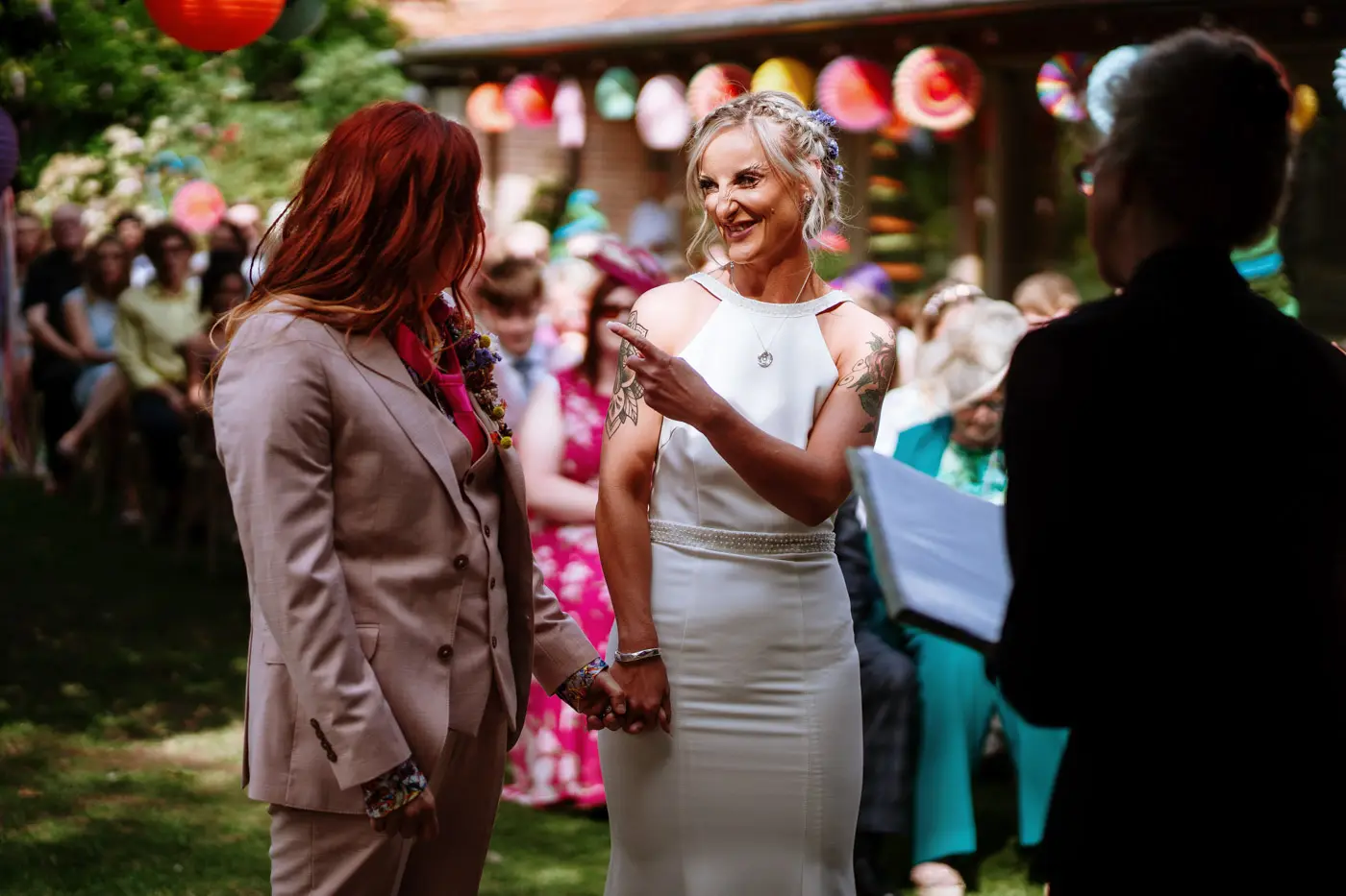 Amy pointing at Abby with a huge smile during their wedding ceremony at Doddington Hall, Lincolnshire