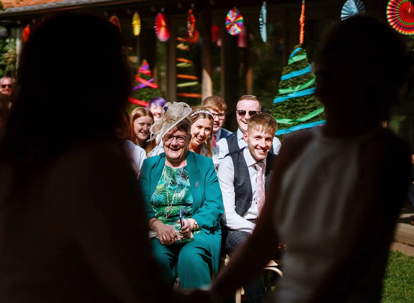 Amy's mum, son and guests looking on with smiles during the wedding ceremony at Doddington Hall, Lincolnshire