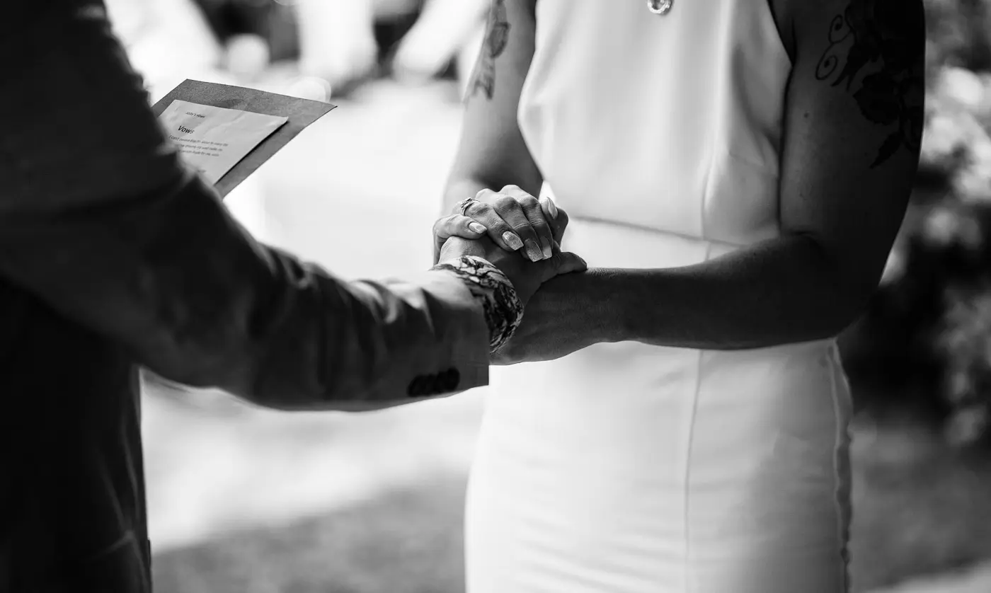 Close detail of Amy and Abby holding hands as they read their vows during their wedding ceremony at Doddington Hall, Lincolnshire