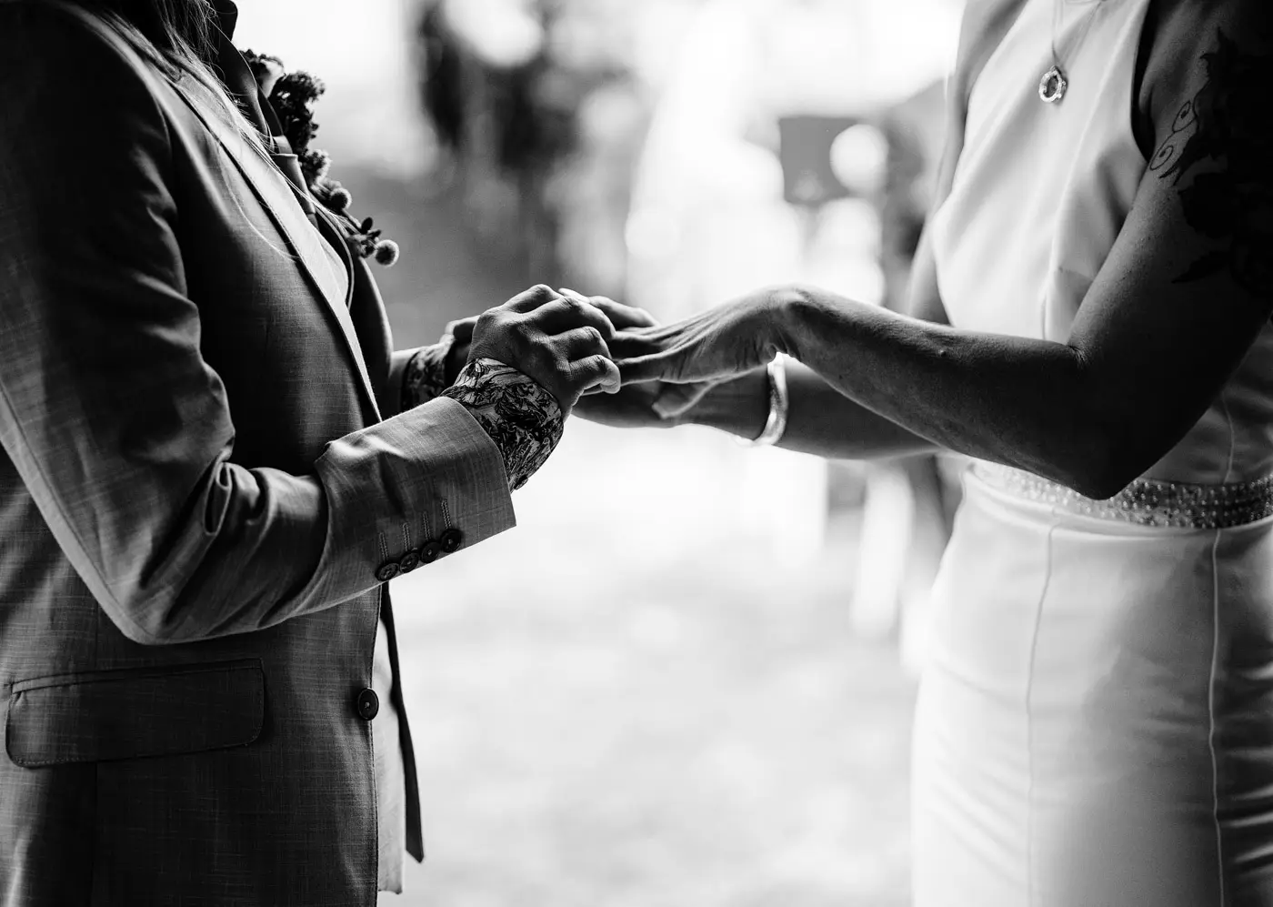 Black and white close up of Abby placing the wedding ring on Amy's finger during their ceremony at Doddington Hall, Lincolnshire