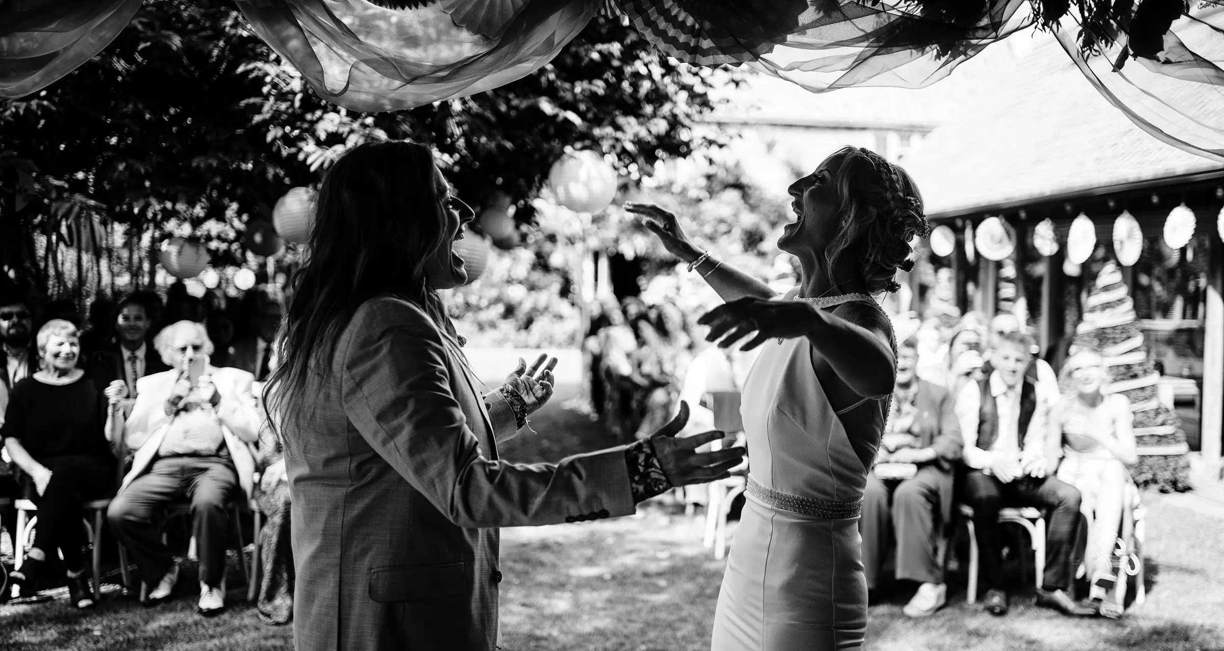 Amy and Abby throwing their arms around each other the moment they are pronounced married at Doddington Hall, Lincolnshire, documentary wedding photography by Gary Phillip