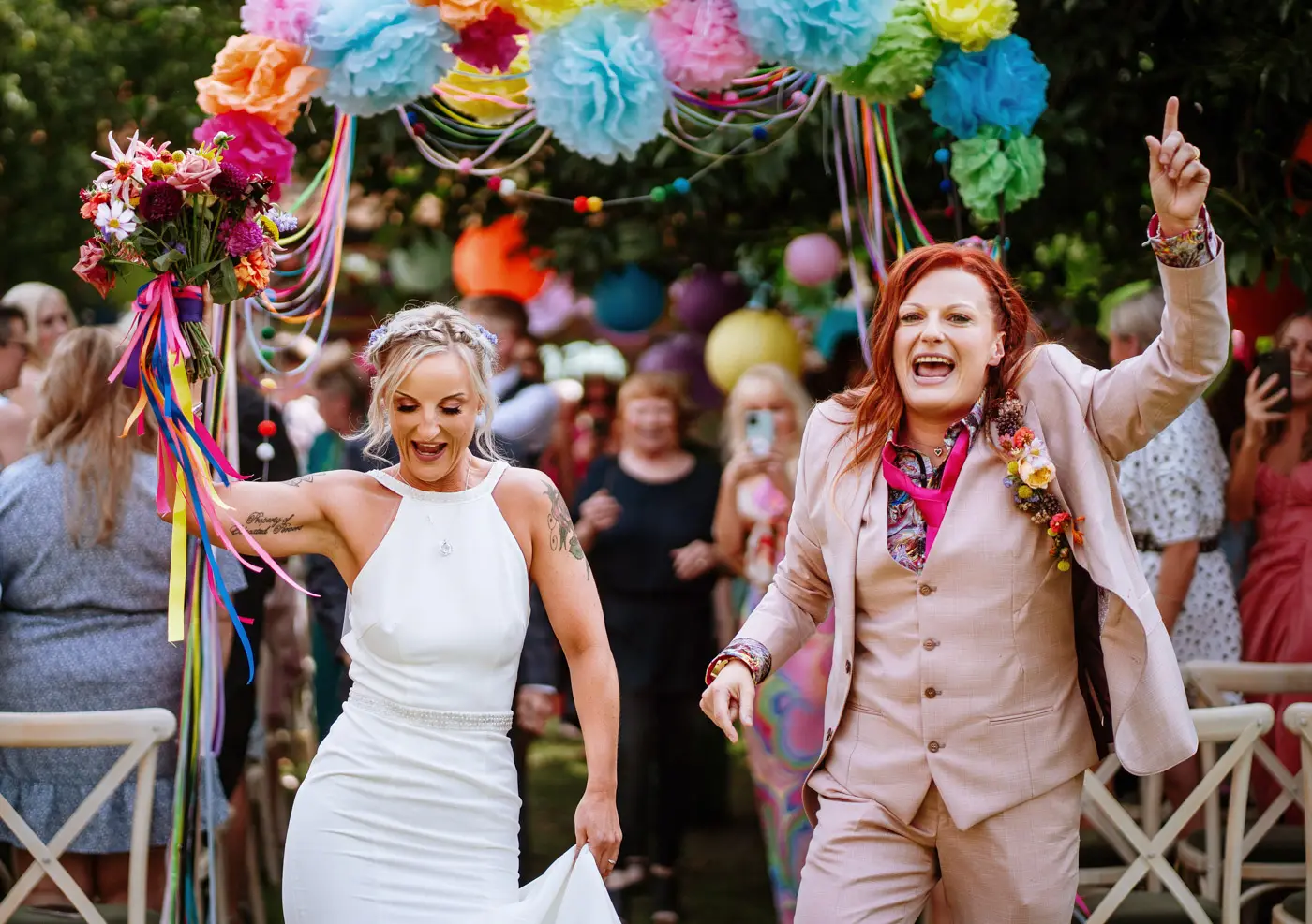 Amy and Abby hitting the end of the aisle and dancing away together at Doddington Hall, Lincolnshire after their wedding ceremony
