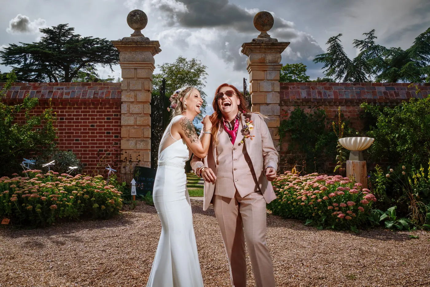 Amy and Abby laughing hard together in the gardens of Doddington Hall, Lincolnshire, a joyful wedding portrait by Gary Phillip