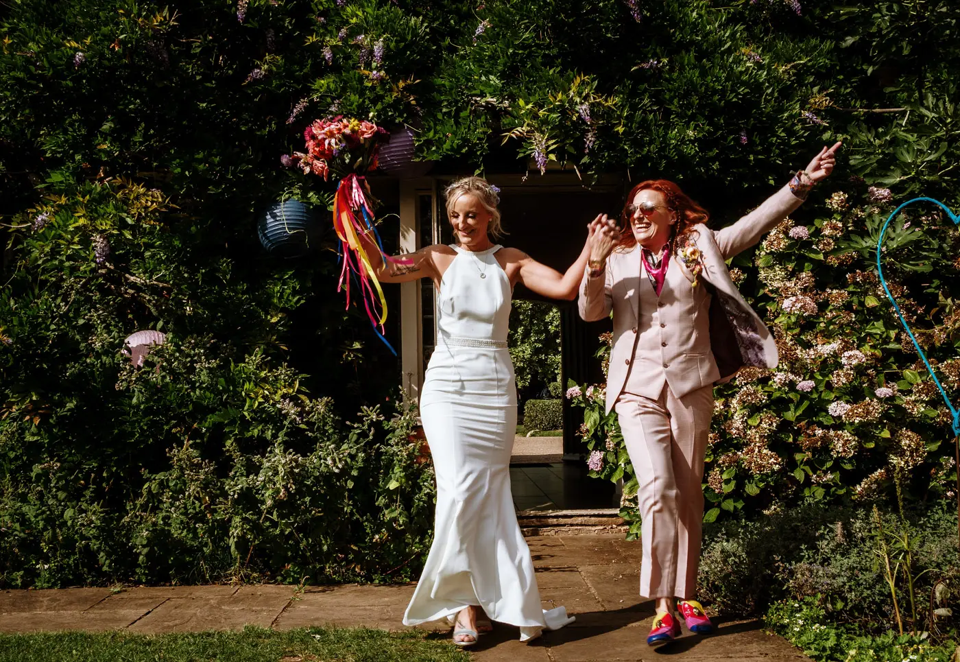 Amy and Abby dancing back into the wedding party in the coach house garden at Doddington Hall, Lincolnshire