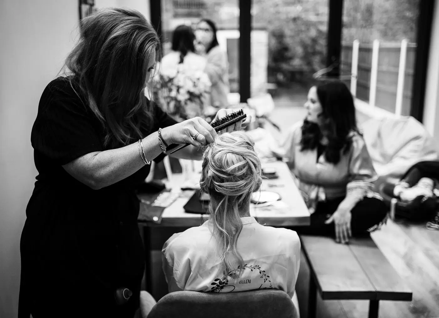 Bride Ellen at home having her hair styled by her hairdresser on her wedding morning in Nottinghamshire