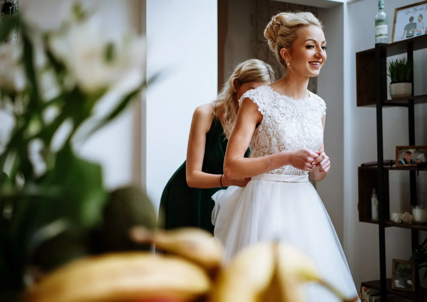 Bride Ellen downstairs having the back of her wedding dress fastened before departing for Carriage Hall, Nottinghamshire