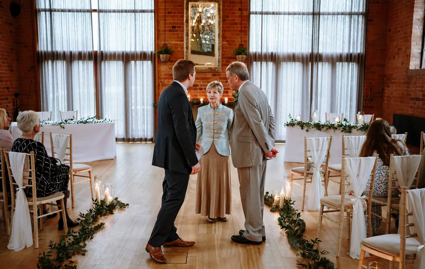 Mother and father of the groom chatting with the best man before the wedding ceremony at Carriage Hall, Nottinghamshire