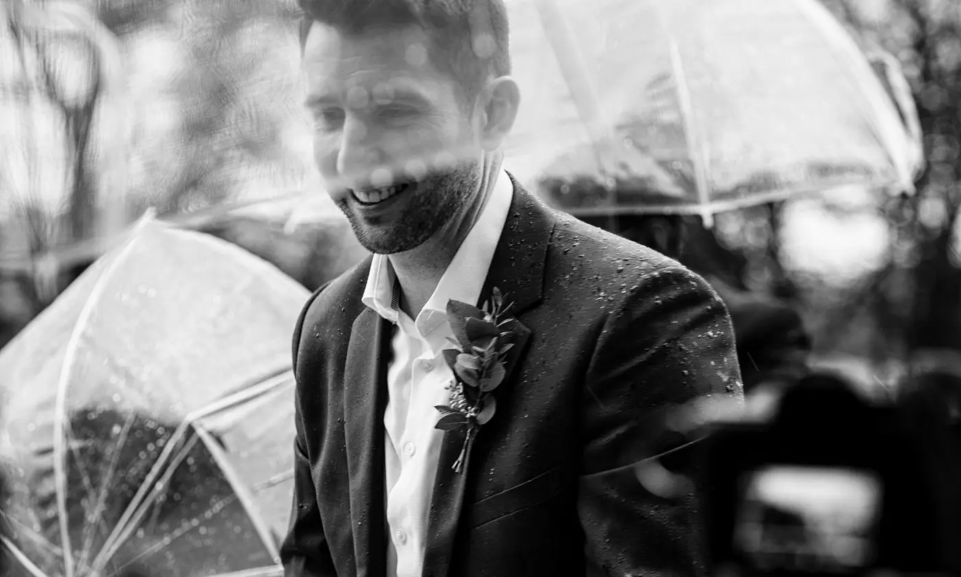 Another best man ready with an umbrella over his face helping guests arrive at Carriage Hall on Ellen and Ben's February wedding day