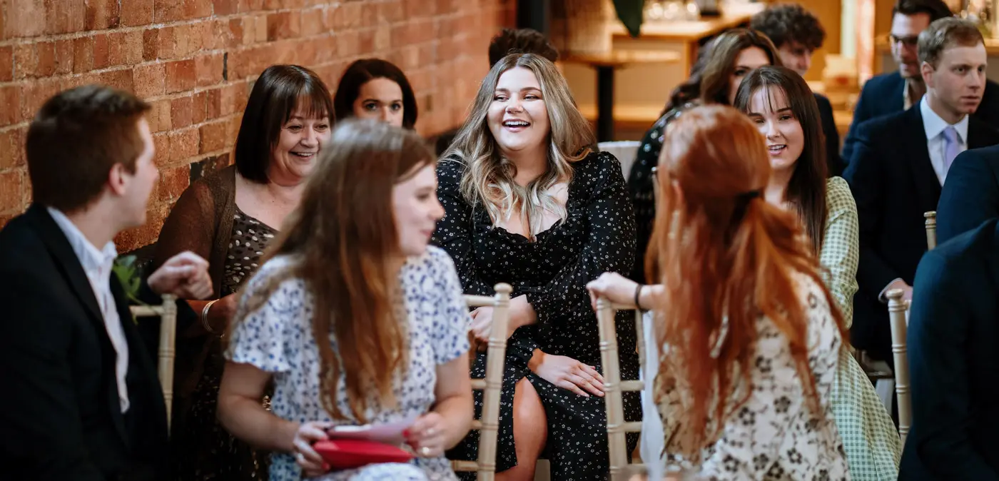 Wedding guests laughing together while they wait for the ceremony to begin at Carriage Hall, Nottinghamshire
