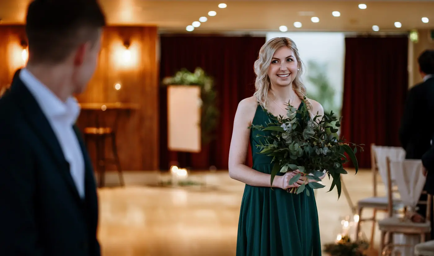A bridesmaid enters the ceremony room while groom Ben greets her warmly at Carriage Hall, Nottinghamshire
