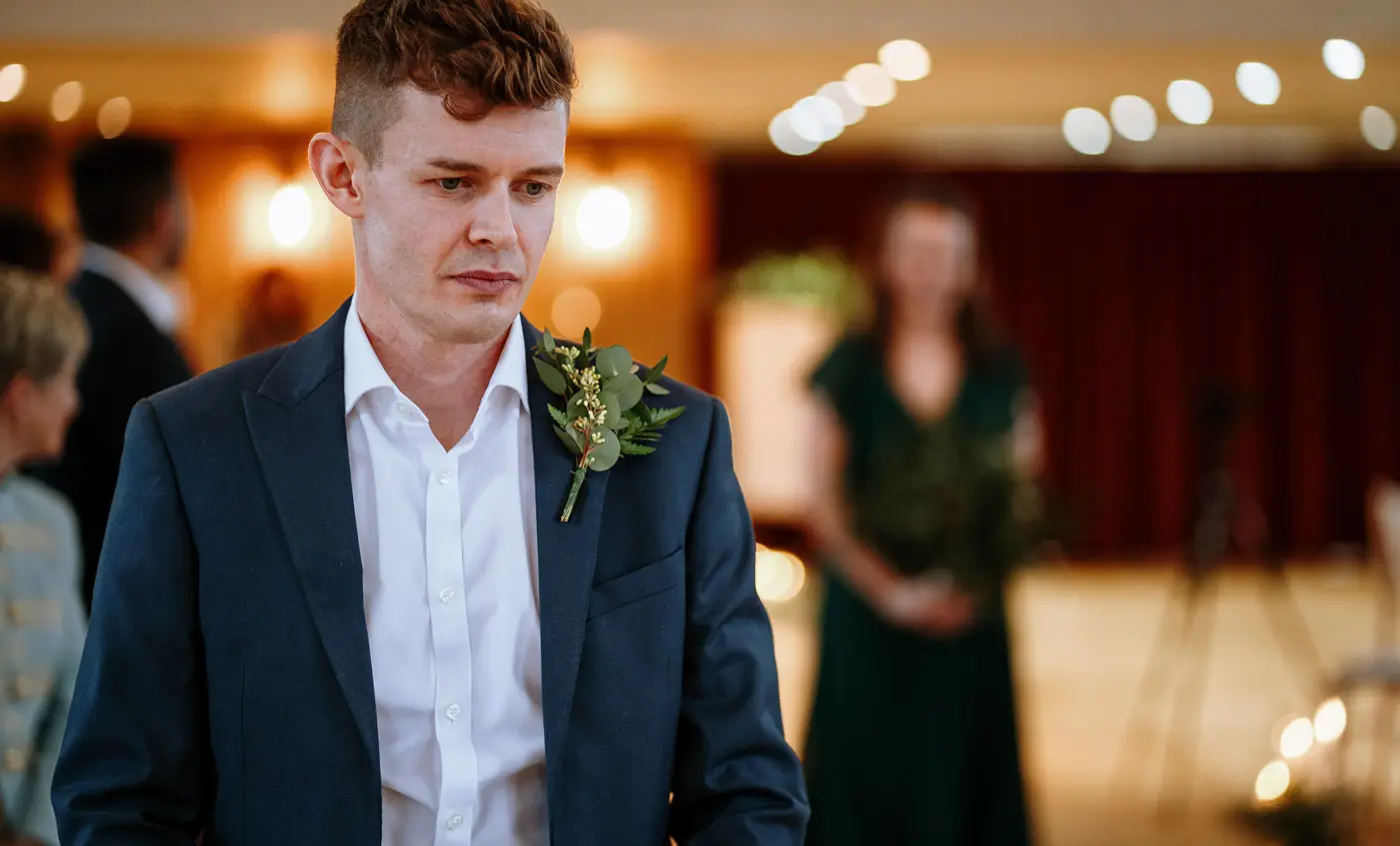 Close portrait of groom Ben waiting nervously for his bride at the front of the ceremony room at Carriage Hall, Nottinghamshire