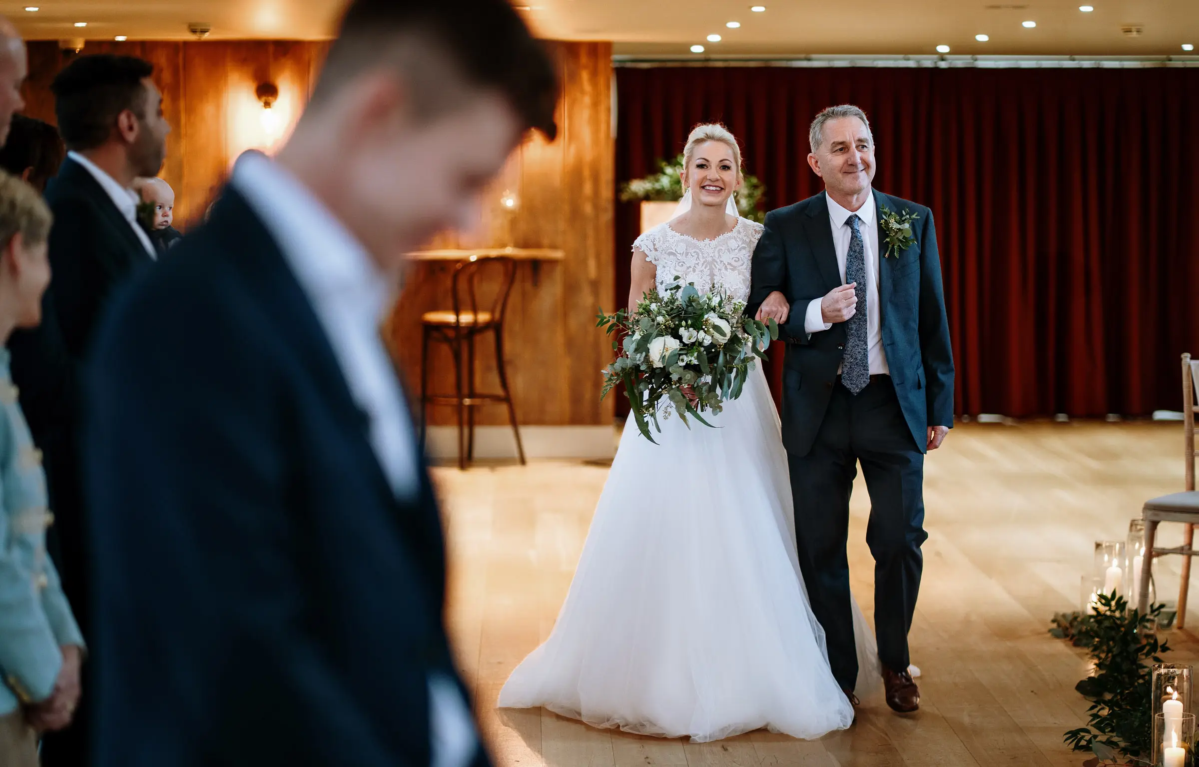 Bride Ellen entering the ceremony room at Carriage Hall with a massive smile on her face as she walks with her father in Nottinghamshire