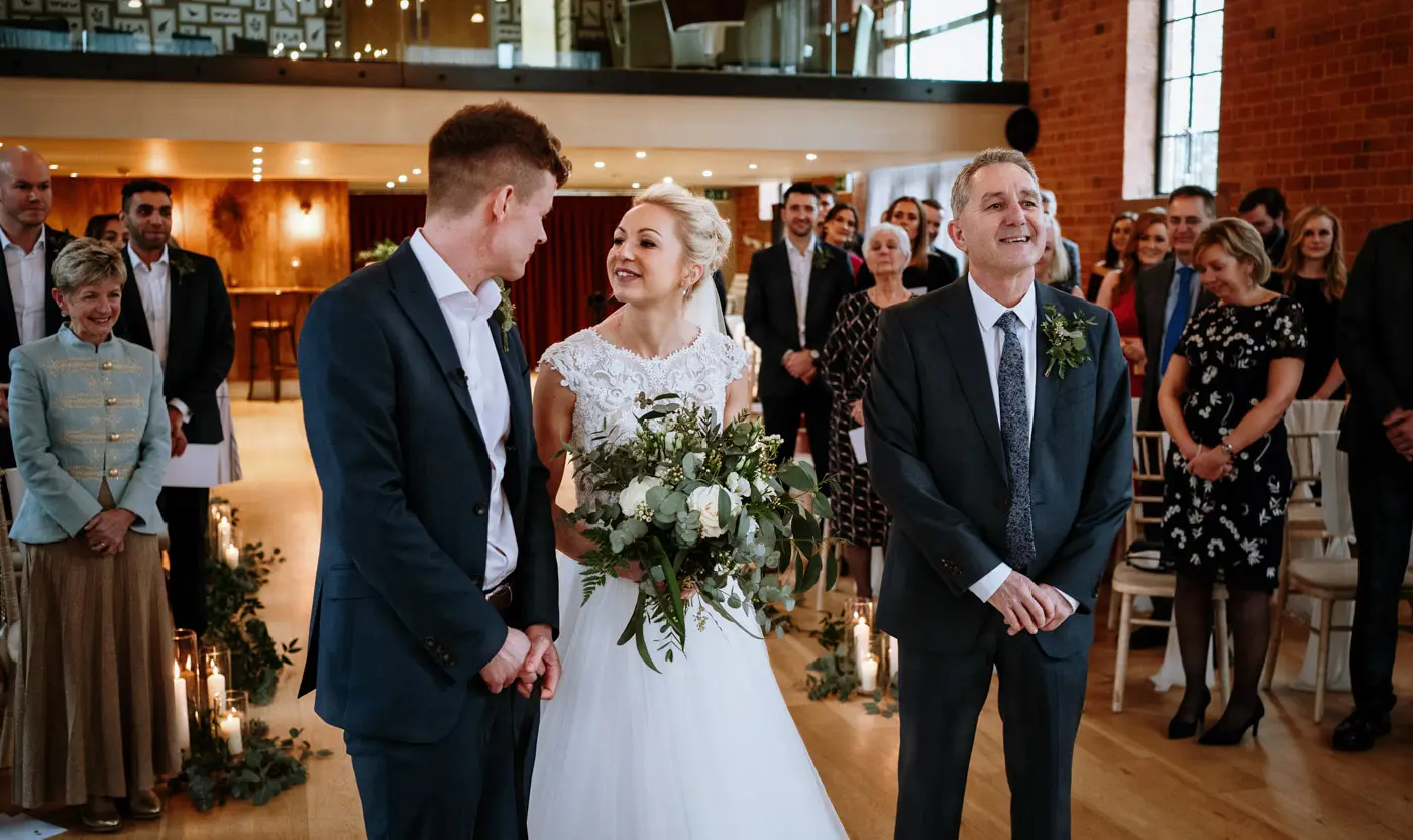 Bride Ellen and groom Ben together at the front of the ceremony room looking into each other's eyes at Carriage Hall, Nottinghamshire