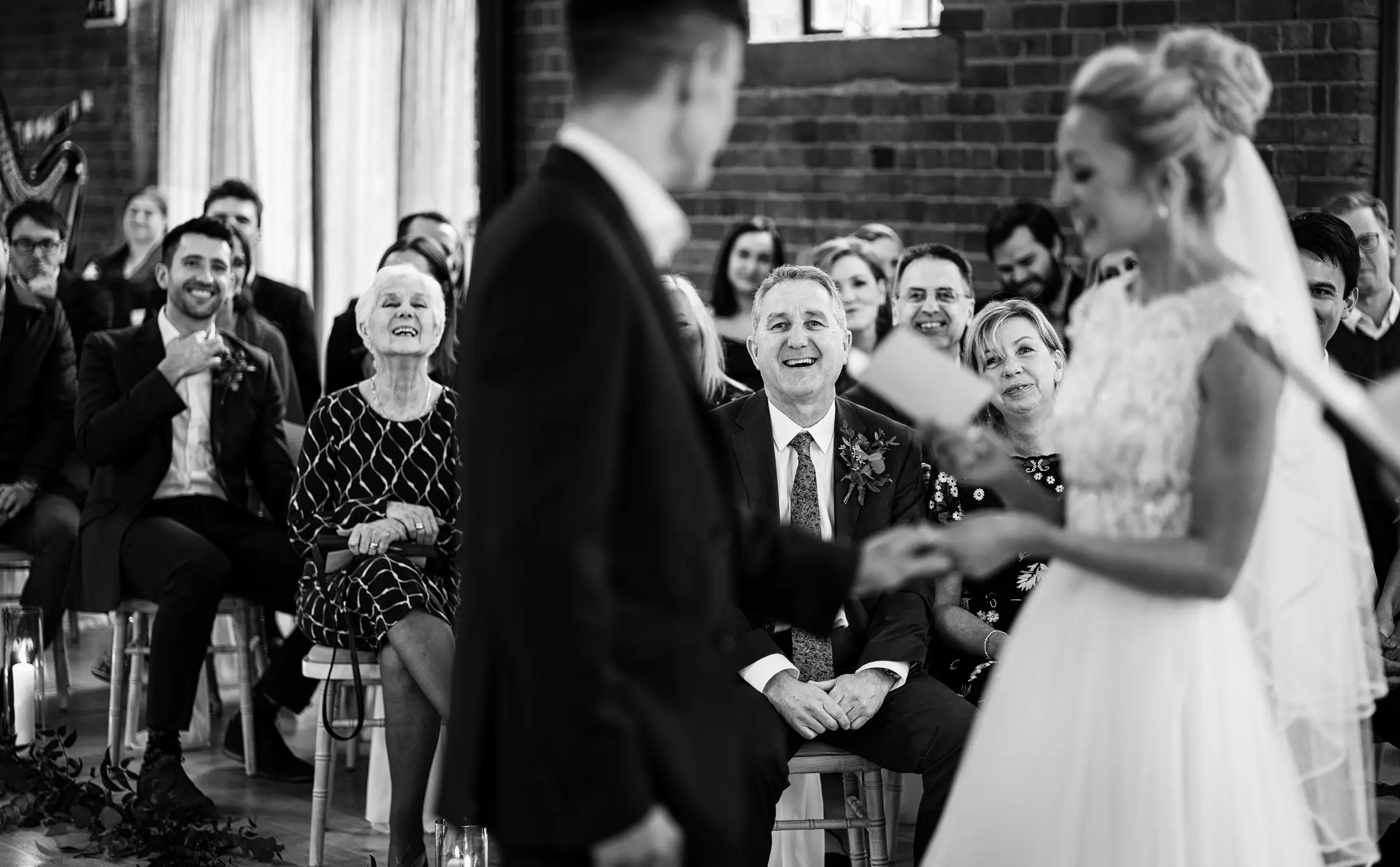 Ellen and Ben slightly out of focus at the front of Carriage Hall with all of their smiling and laughing guests clearly visible behind them