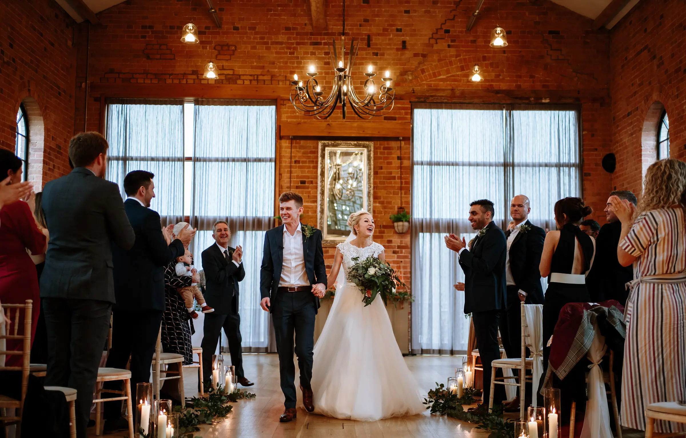 Ellen and Ben walk the recessional with big smiles, married at last, at Carriage Hall, Nottinghamshire