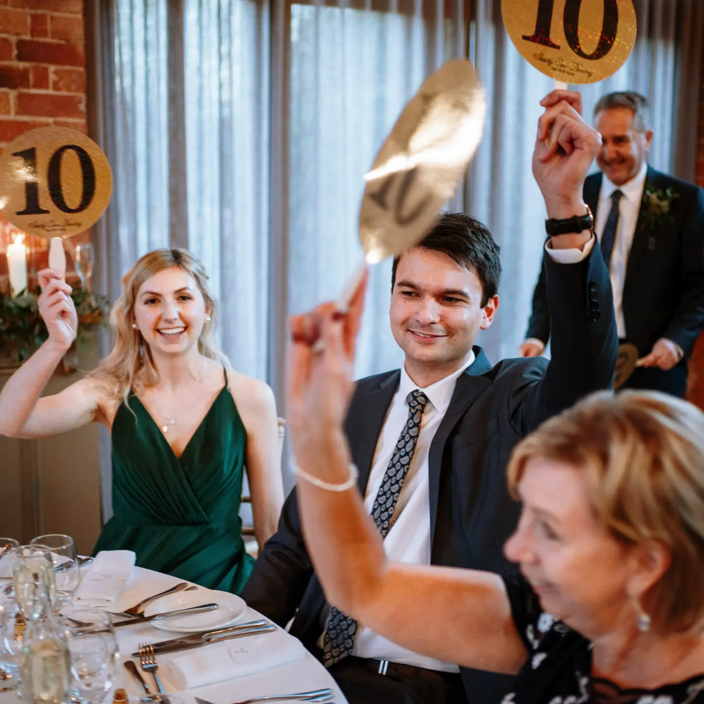 Guests holding up large paddles with 10 on them to score Ellen and Ben a perfect ten out of ten at Carriage Hall, Nottinghamshire