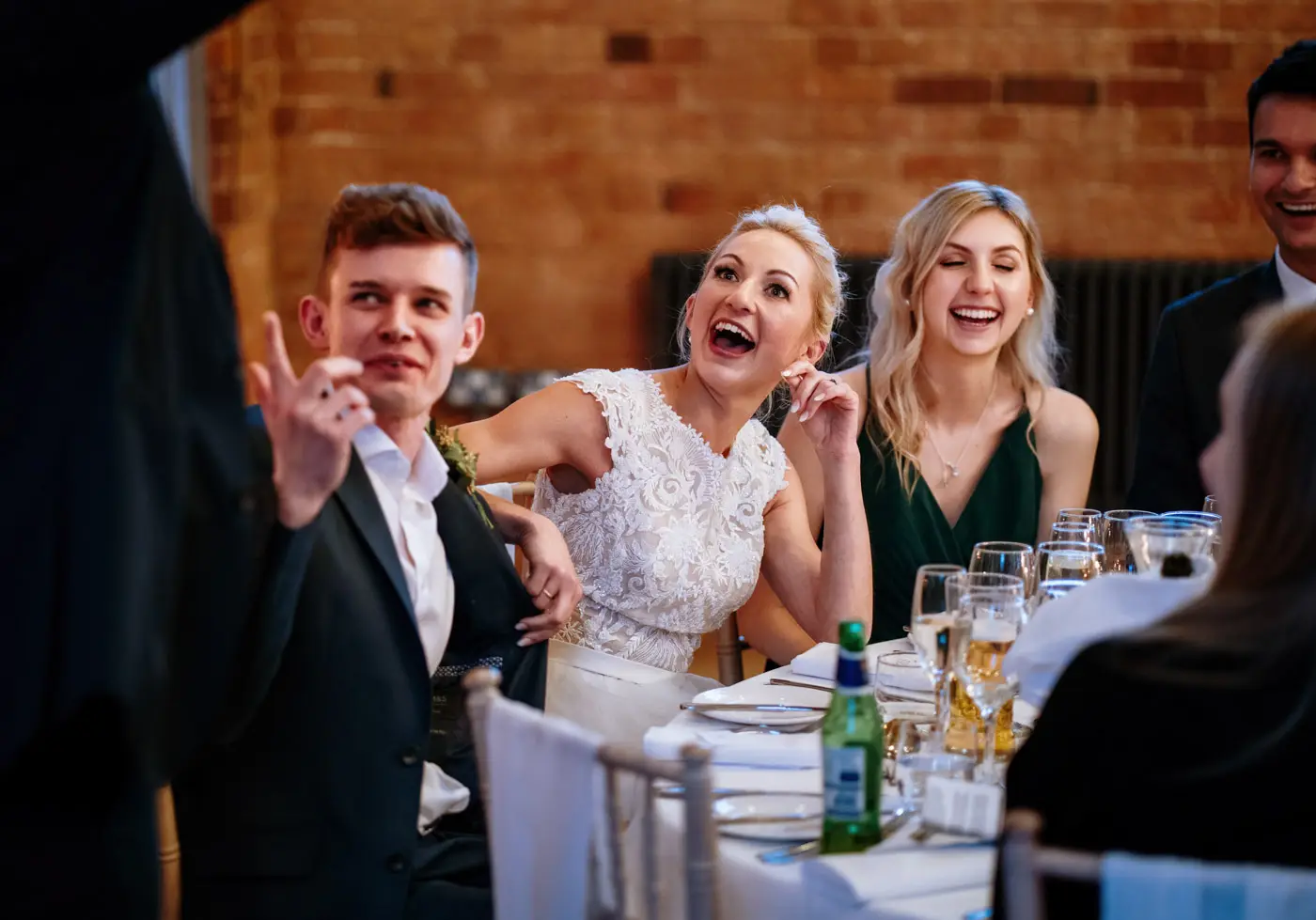 Bride Ellen open-mouthed with laughter at something groom Ben has said during his wedding speech at Carriage Hall, Nottinghamshire