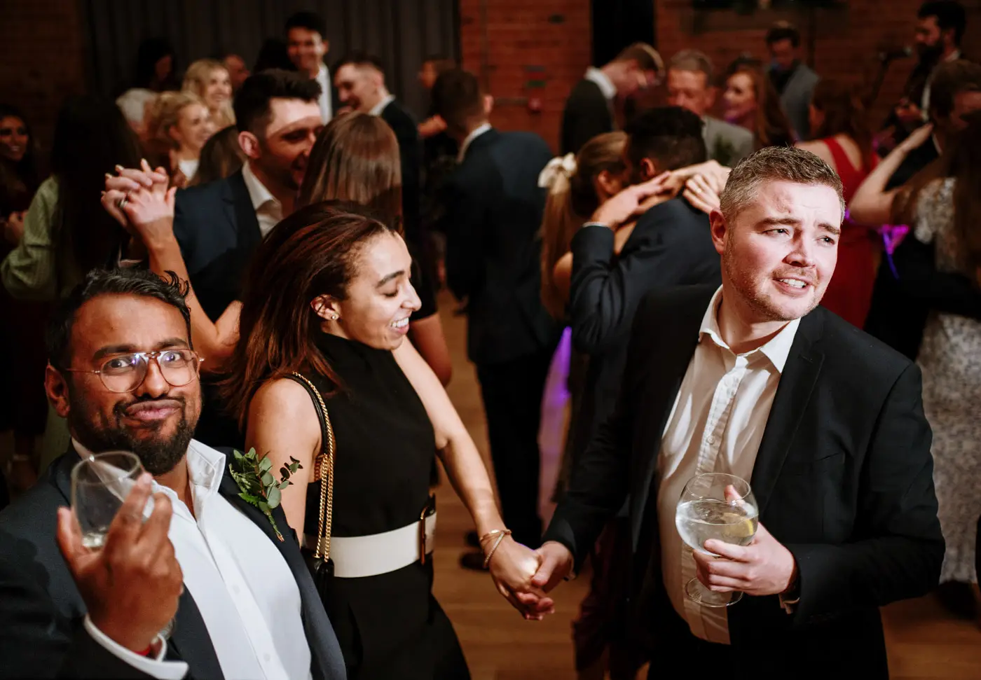 Wedding guests dancing and playing up to the camera on the dancefloor at Carriage Hall, Nottinghamshire