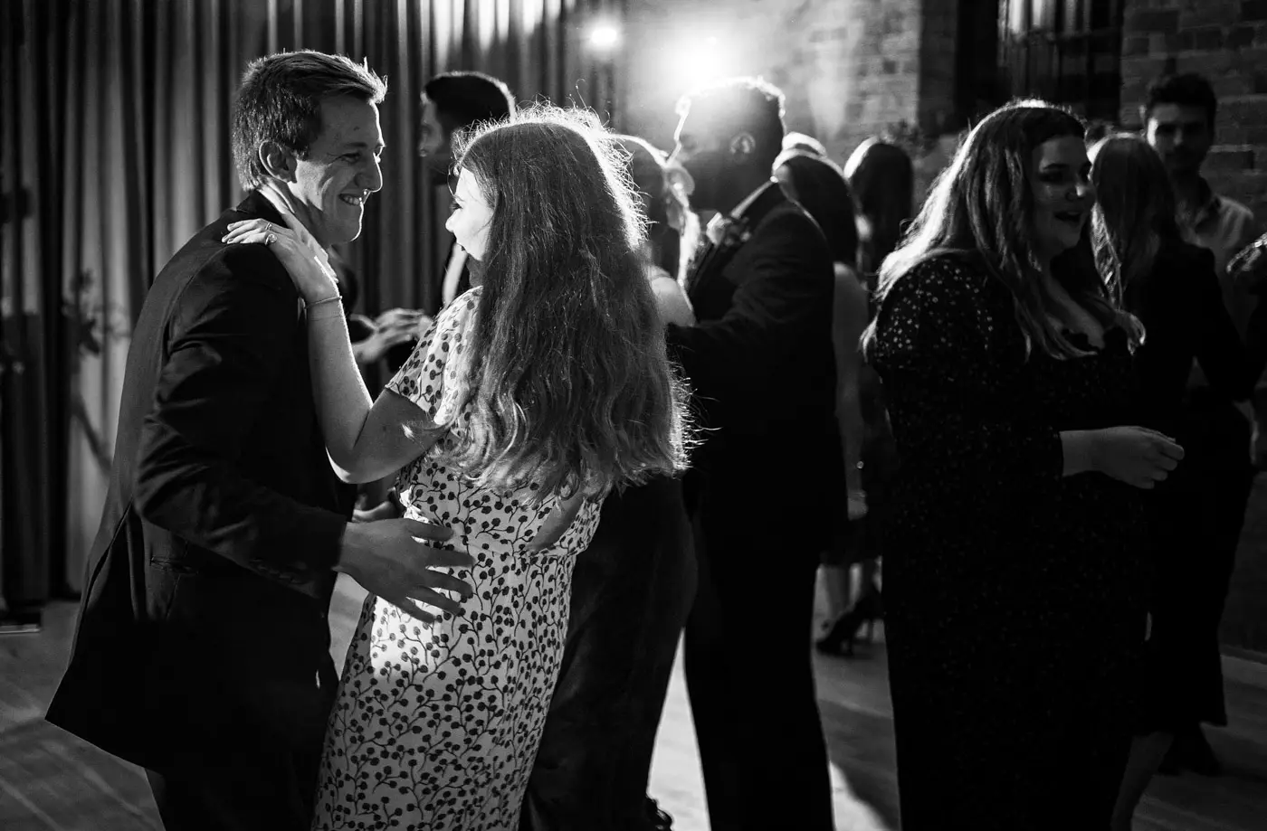 Wedding guests dancing and laughing in each other's arms on the dancefloor at Carriage Hall, Nottinghamshire