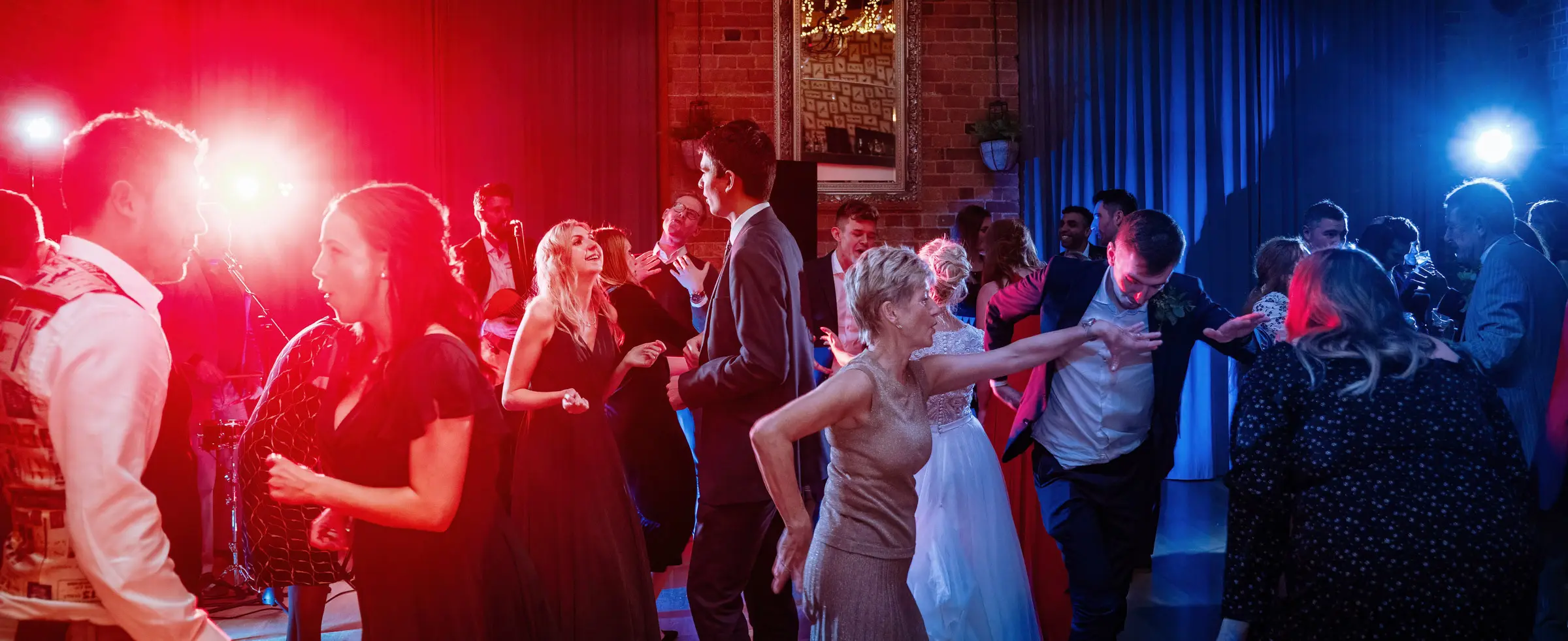 Wide shot of the dancefloor at Carriage Hall with dramatic red light crossing blue light creating a stunning atmosphere at Ellen and Ben's February wedding