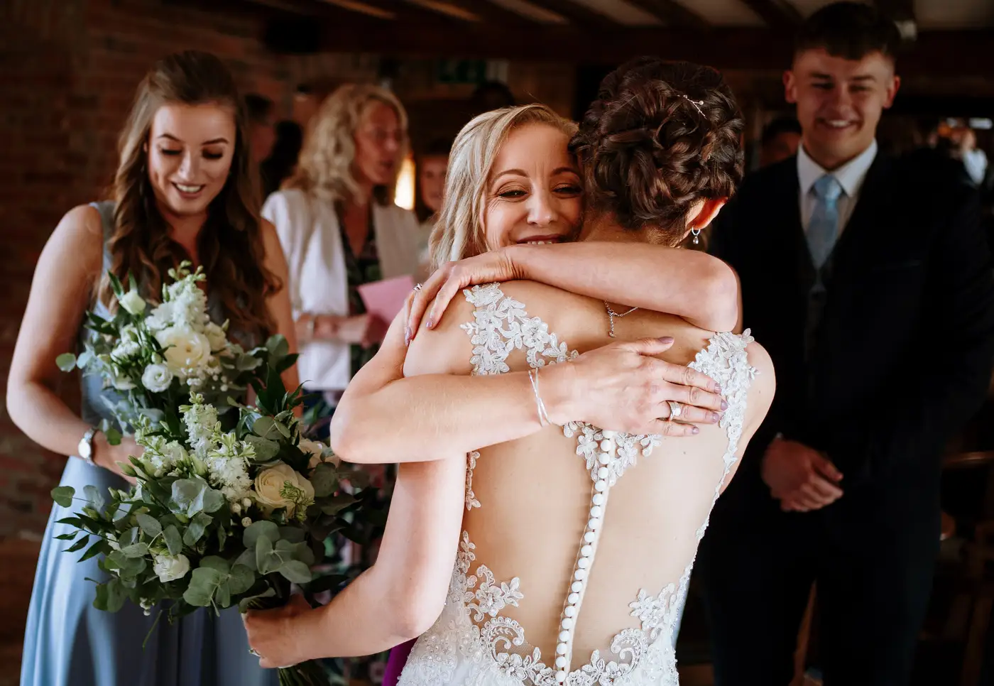Bride Krissie receiving hugs from her mother after the wedding service at Swancar Farm, Nottinghamshire, a warm family moment by Gary Phillip