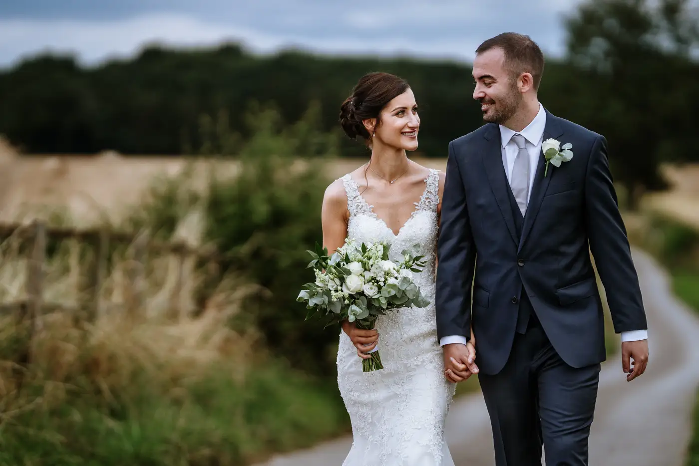 Close up of bride Krissie and groom Tom walking Swancar Farm's long road, an intimate portrait from their Nottinghamshire wedding by Gary Phillip
