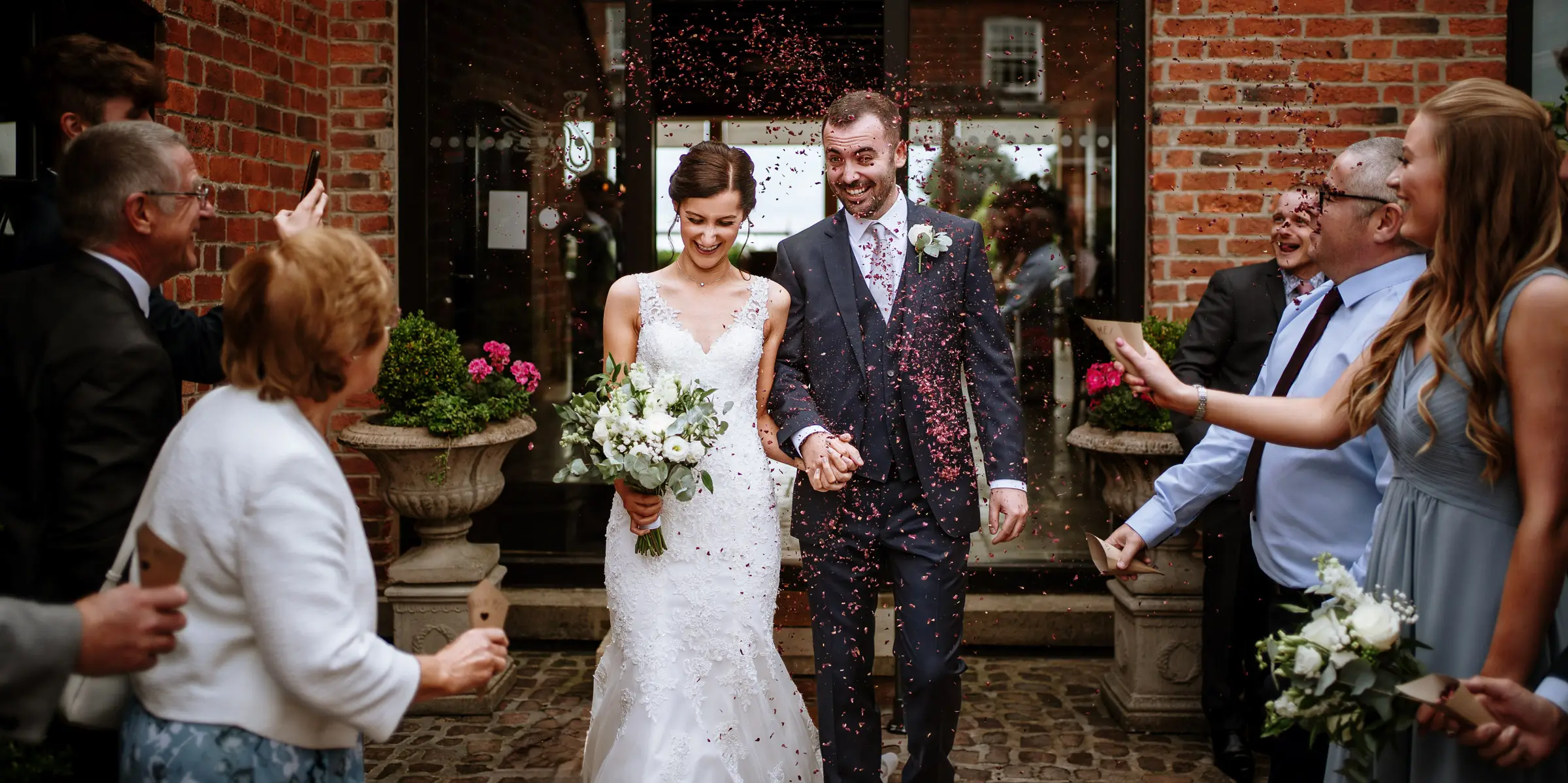Bride Krissie and groom Tom caught in a storm of confetti at Swancar Farm, Nottinghamshire, a joyful celebration moment captured by Gary Phillip