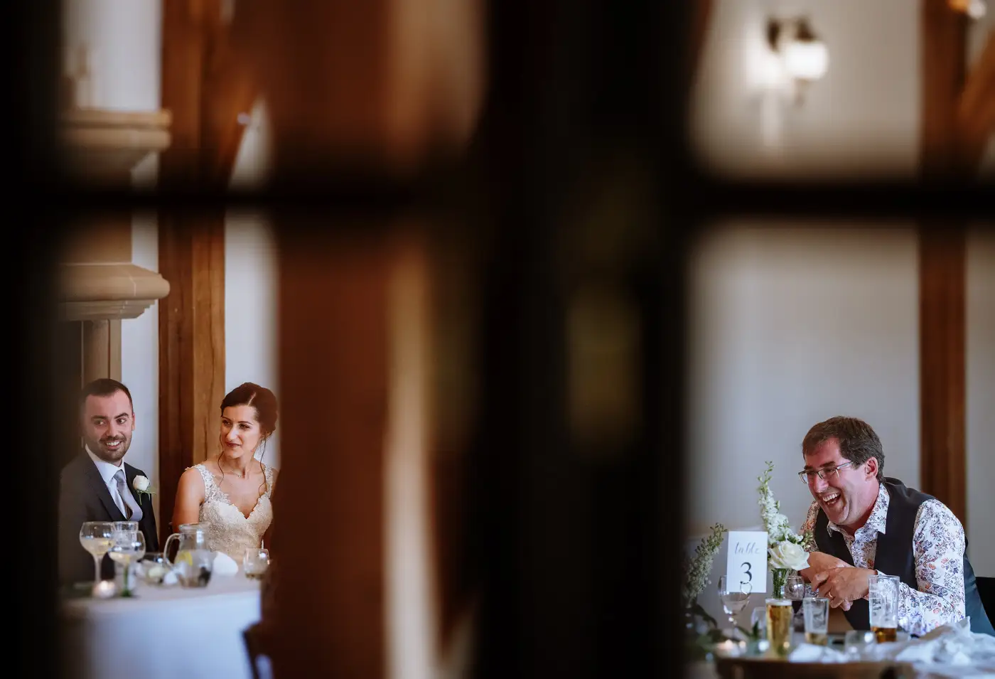Creative split view of Swancar Farm's great hall showing a serene bride and groom alongside a laughing guest, documentary wedding photography by Gary Phillip
