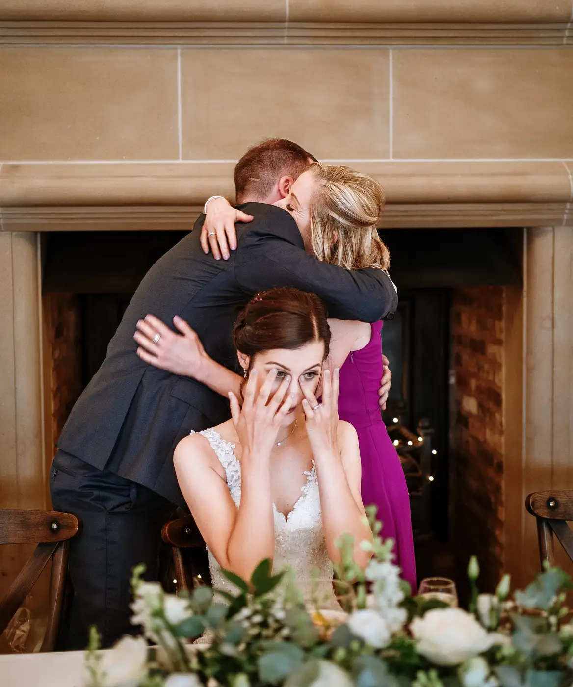 Mother of the bride hugging groom Tom with bride Krissie in the foreground wiping away a tear at Swancar Farm, a layered emotional moment by Gary Phillip