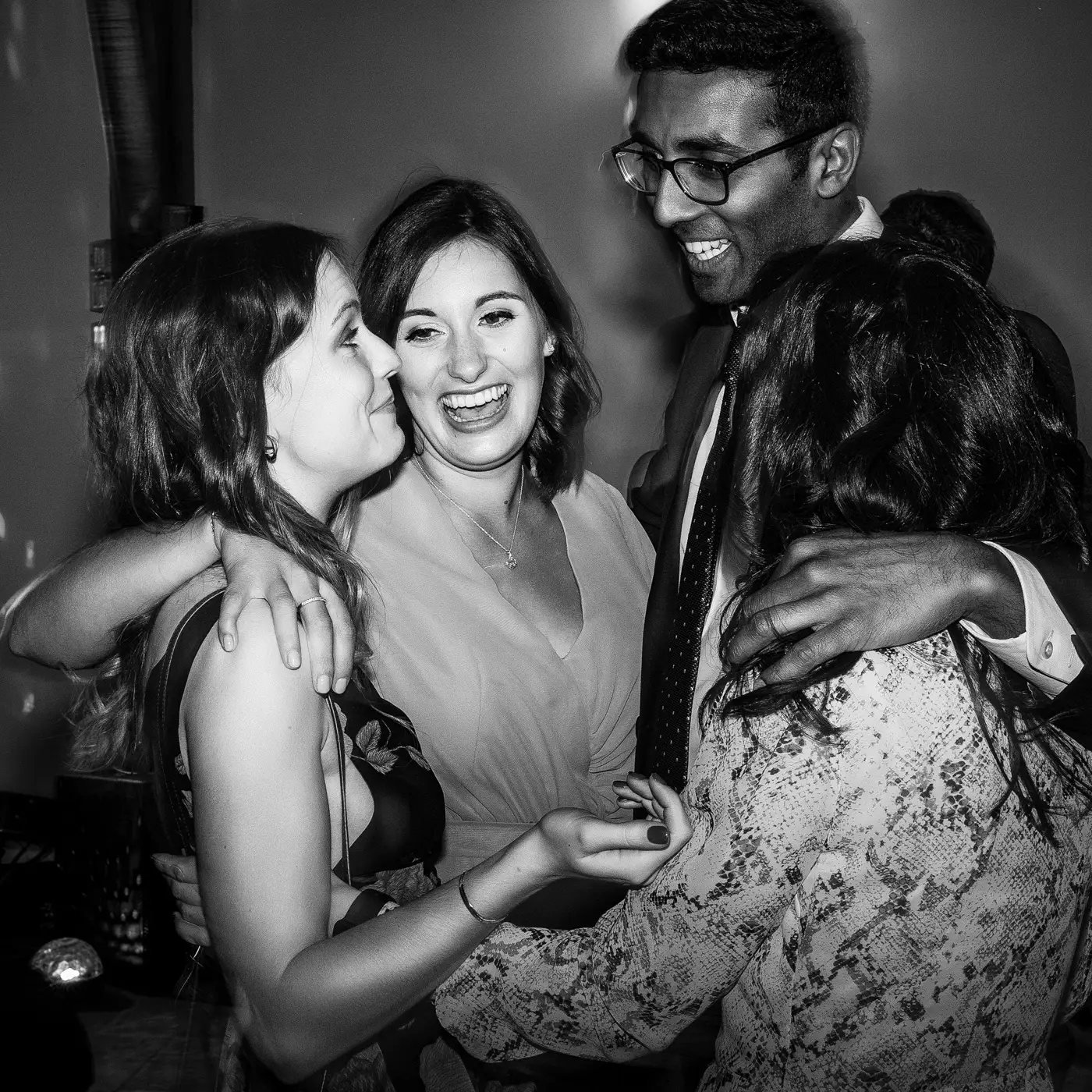 Wedding guests gathered together in a huddle enjoying the evening celebrations at Swancar Farm, candid documentary wedding photography by Gary Phillip