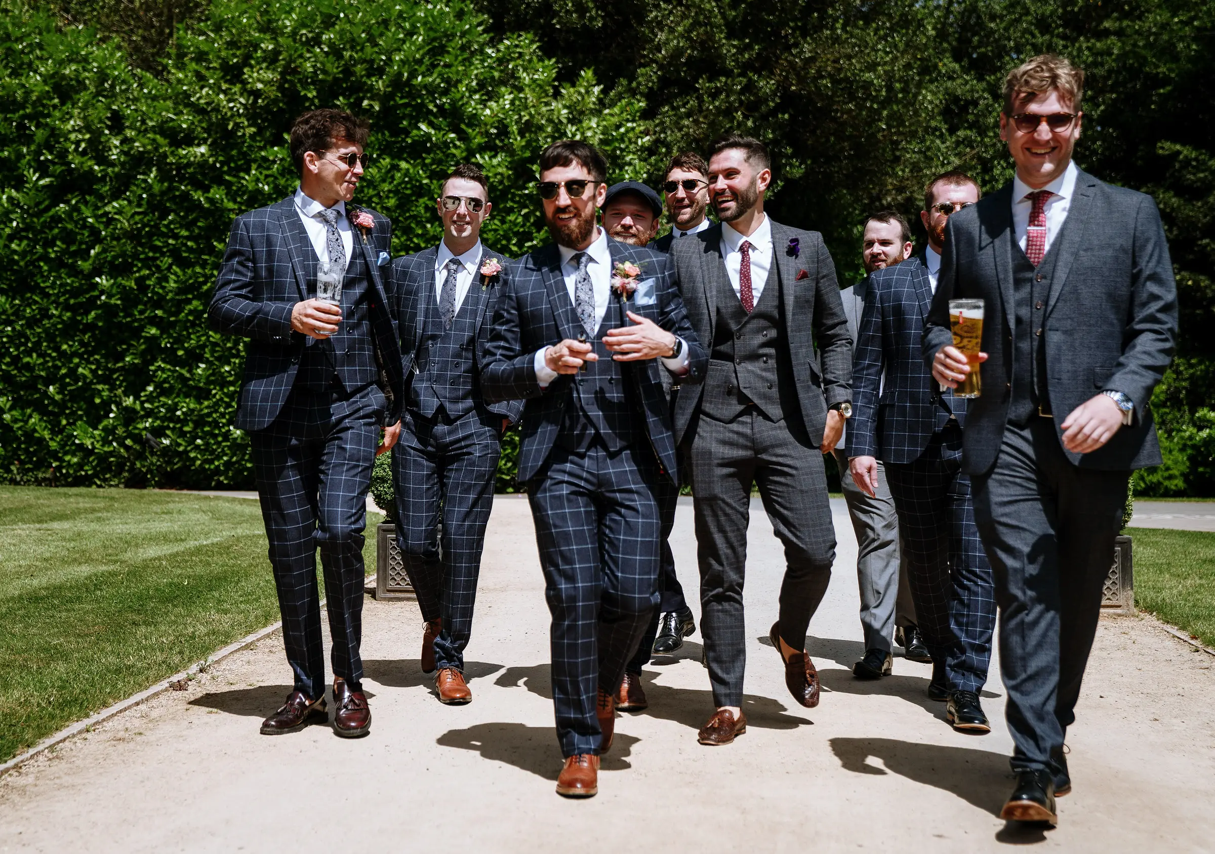 Groom Gavin and his nine groomsmen walking together to The Walled Garden at Beeston Fields looking like the Peaky Blinders, a standout wedding morning moment