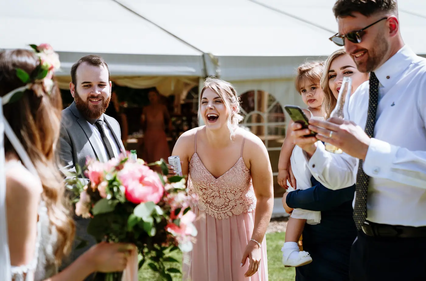 Bridesmaid and guests laughing with bride Laura after the ceremony at The Walled Garden at Beeston Fields, Nottingham