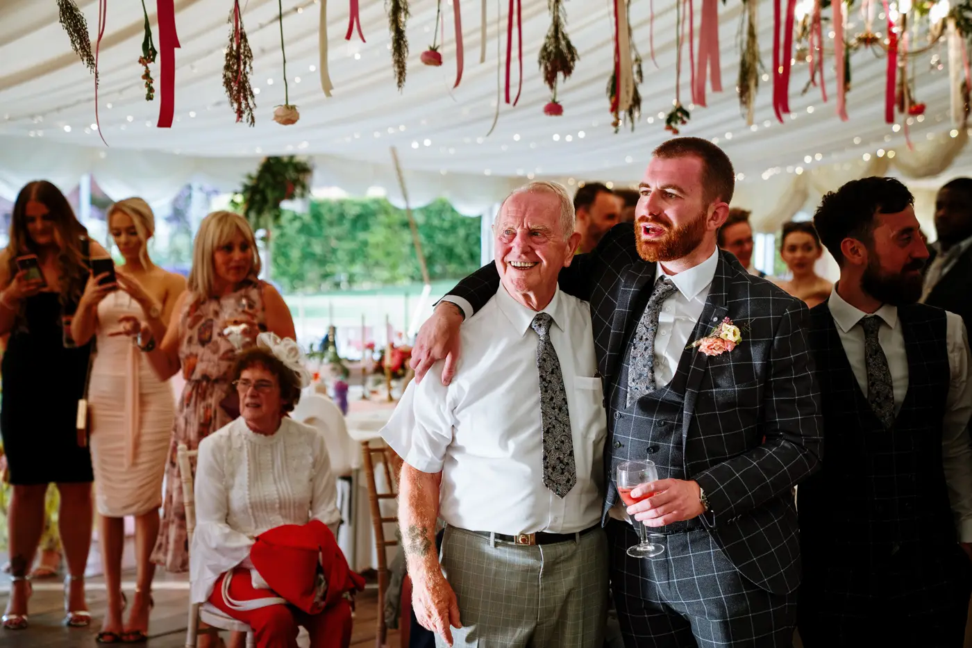 An usher with his arm around grandad watching bride Laura dance with her father at The Walled Garden at Beeston Fields, Nottingham