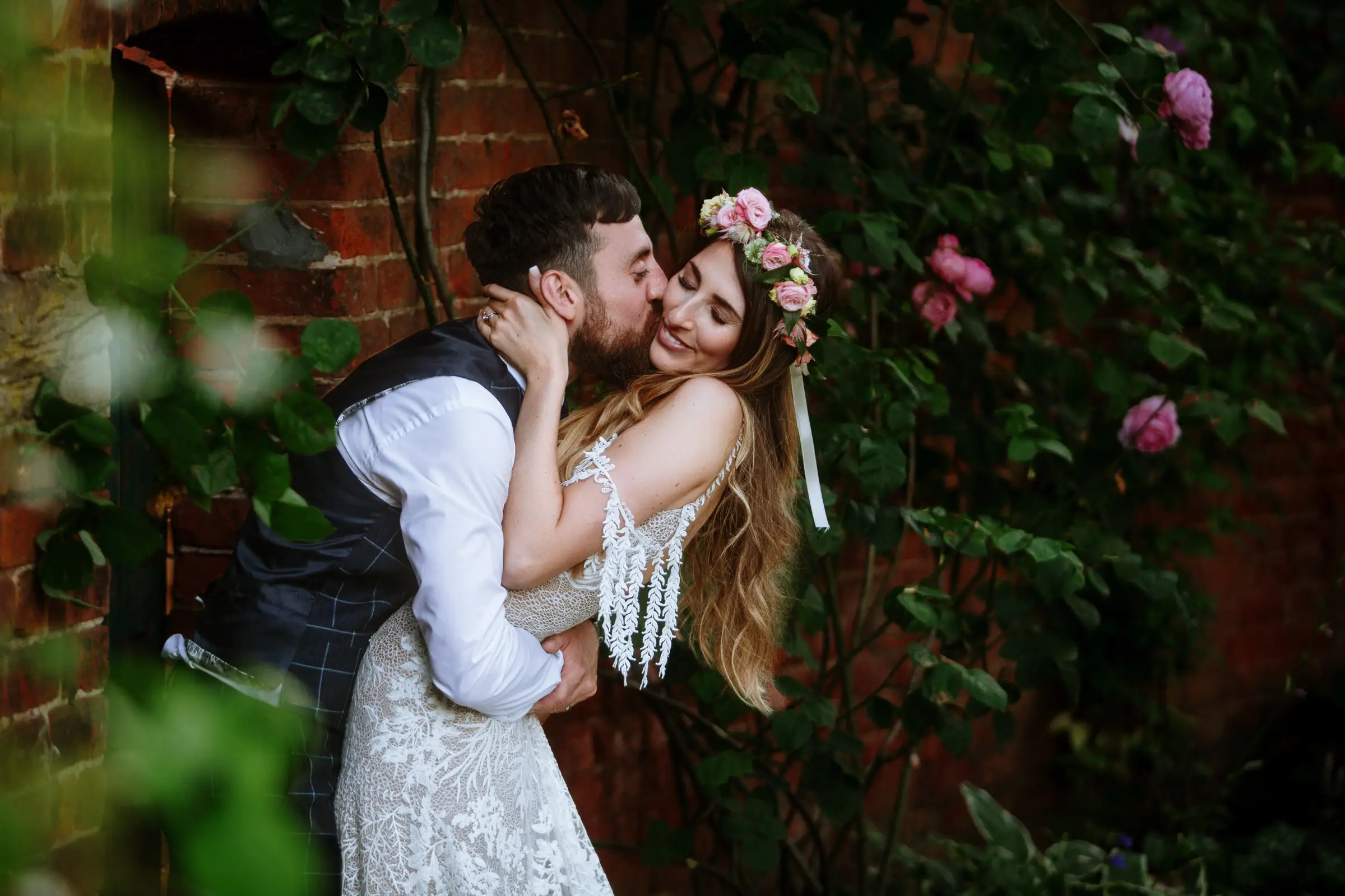 Bride Laura and groom Gavin in a close S-shaped embrace in the walled garden at Beeston Fields, Nottingham, with Laura loving every moment of her wedding day