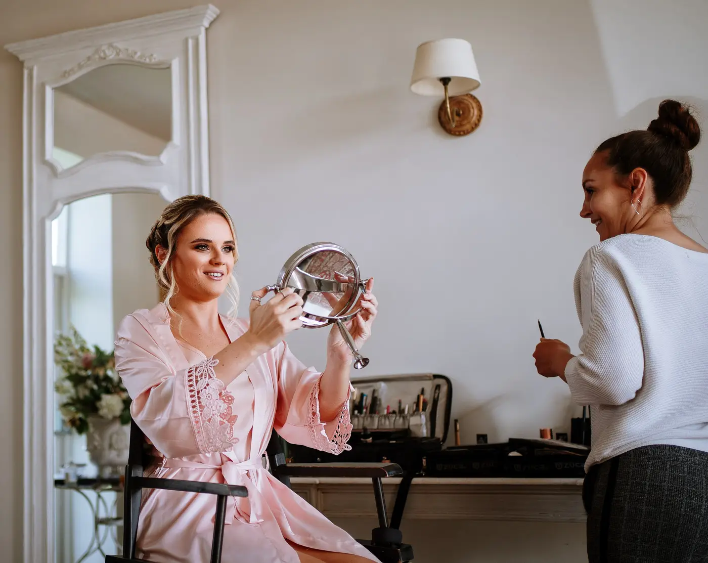 A bridesmaid checking out her finished makeup in the mirror on the morning of Louise and Martin's wedding at Doddington Hall