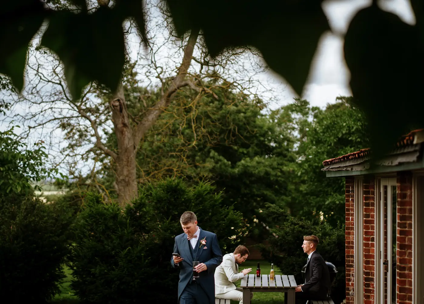 Guests and ushers gathering outside Doddington Hall sharing a moment before the wedding ceremony in Lincolnshire