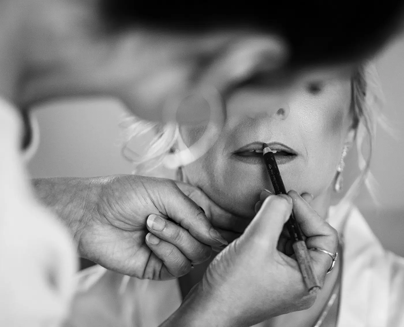 Mother of the bride having her lipstick applied on the wedding morning before Louise and Martin's ceremony at Doddington Hall