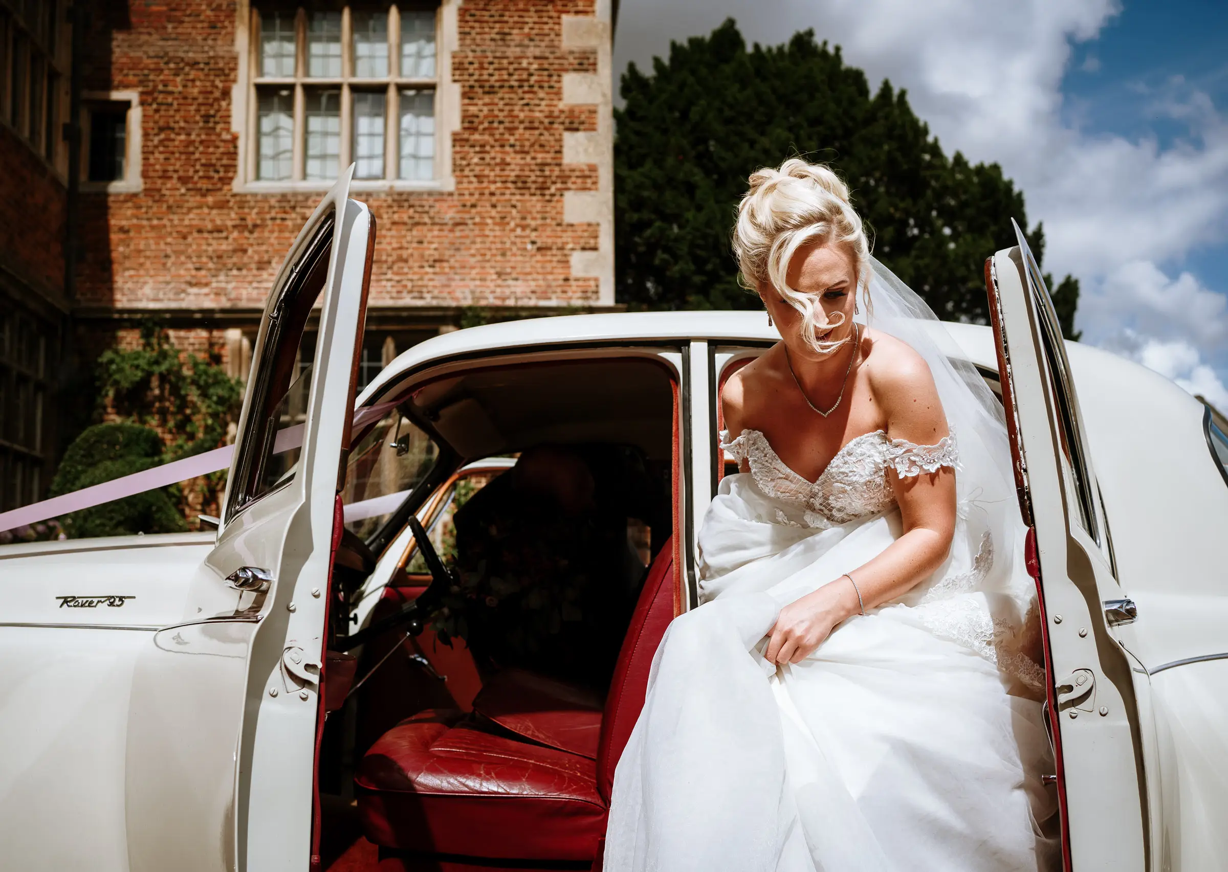 Bride Louise stepping out of the wedding car in front of Doddington Hall, Lincolnshire on her wedding day, photographed by Gary Phillip