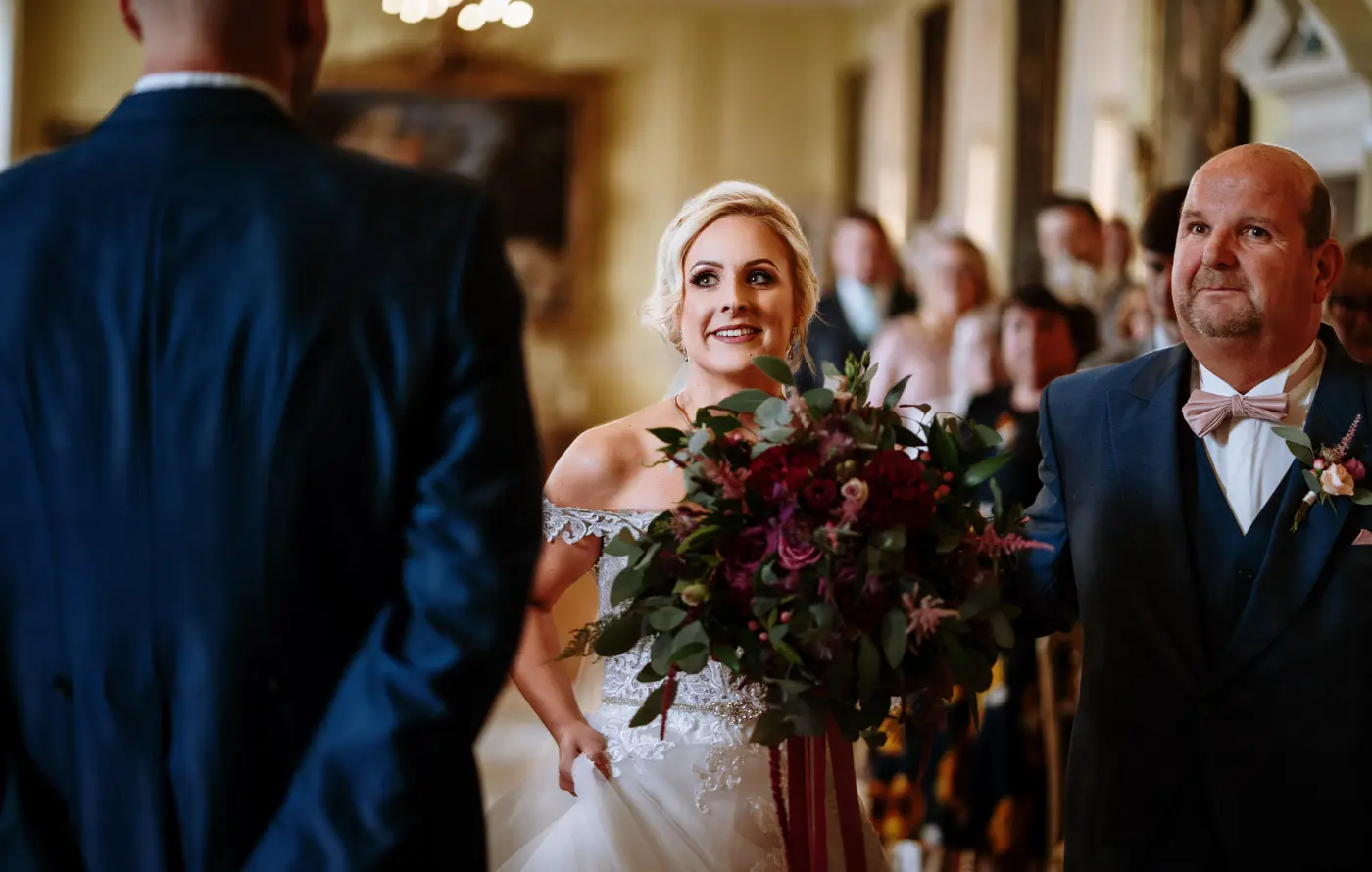 Bride Louise arriving at the front of the Long Gallery at Doddington Hall to meet her future husband Martin during their wedding ceremony
