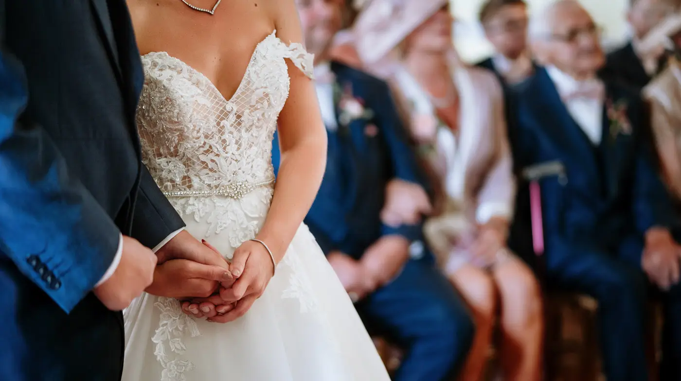 Close detail of bride Louise and groom Martin holding hands during their wedding ceremony in the Long Gallery at Doddington Hall, Lincolnshire