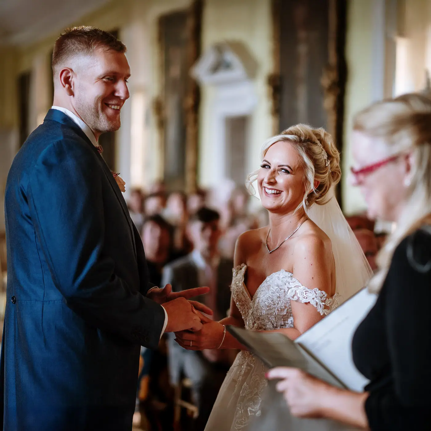 Bride Louise and groom Martin laughing again with the registrar during their wedding ceremony at Doddington Hall, Lincolnshire