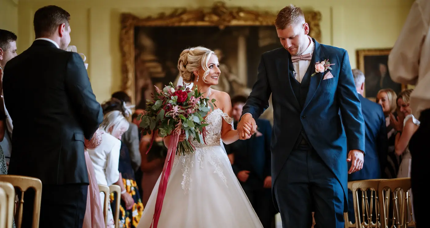 Bride Louise and groom Martin walking the recessional together as a married couple at Doddington Hall, Lincolnshire