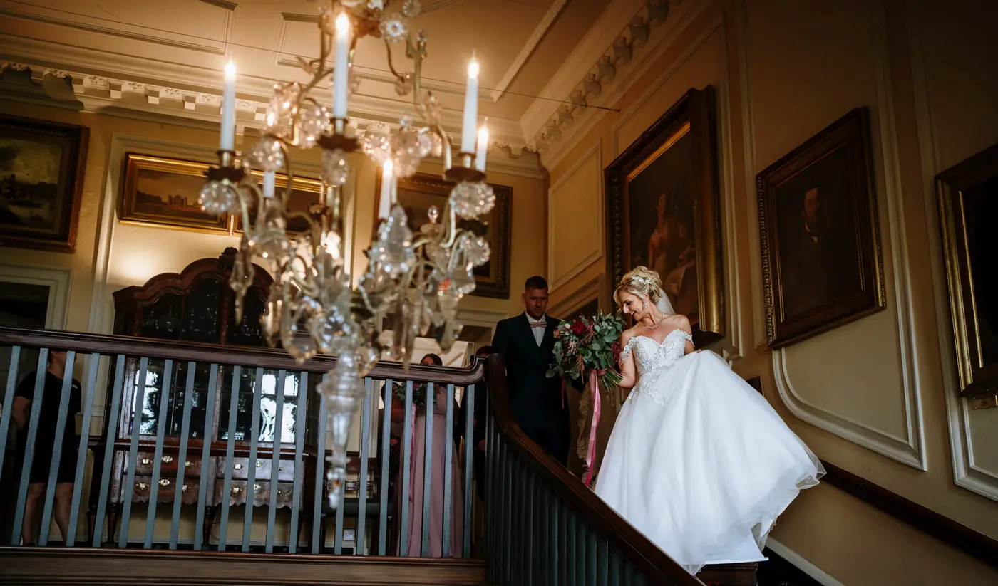 Bride Louise and groom Martin making their way down the grand staircase at Doddington Hall as a married couple, Lincolnshire