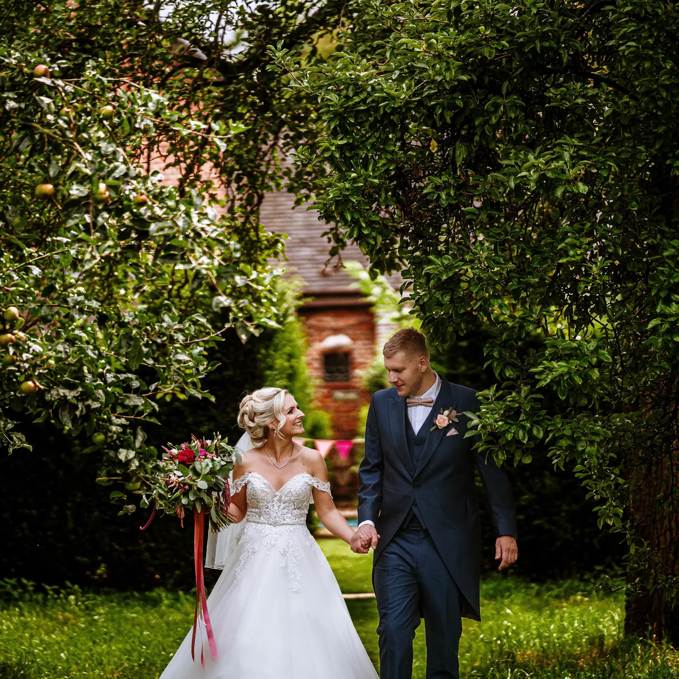 Bride Louise and groom Martin continuing their walk through the stunning grounds of Doddington Hall, Lincolnshire on their wedding day