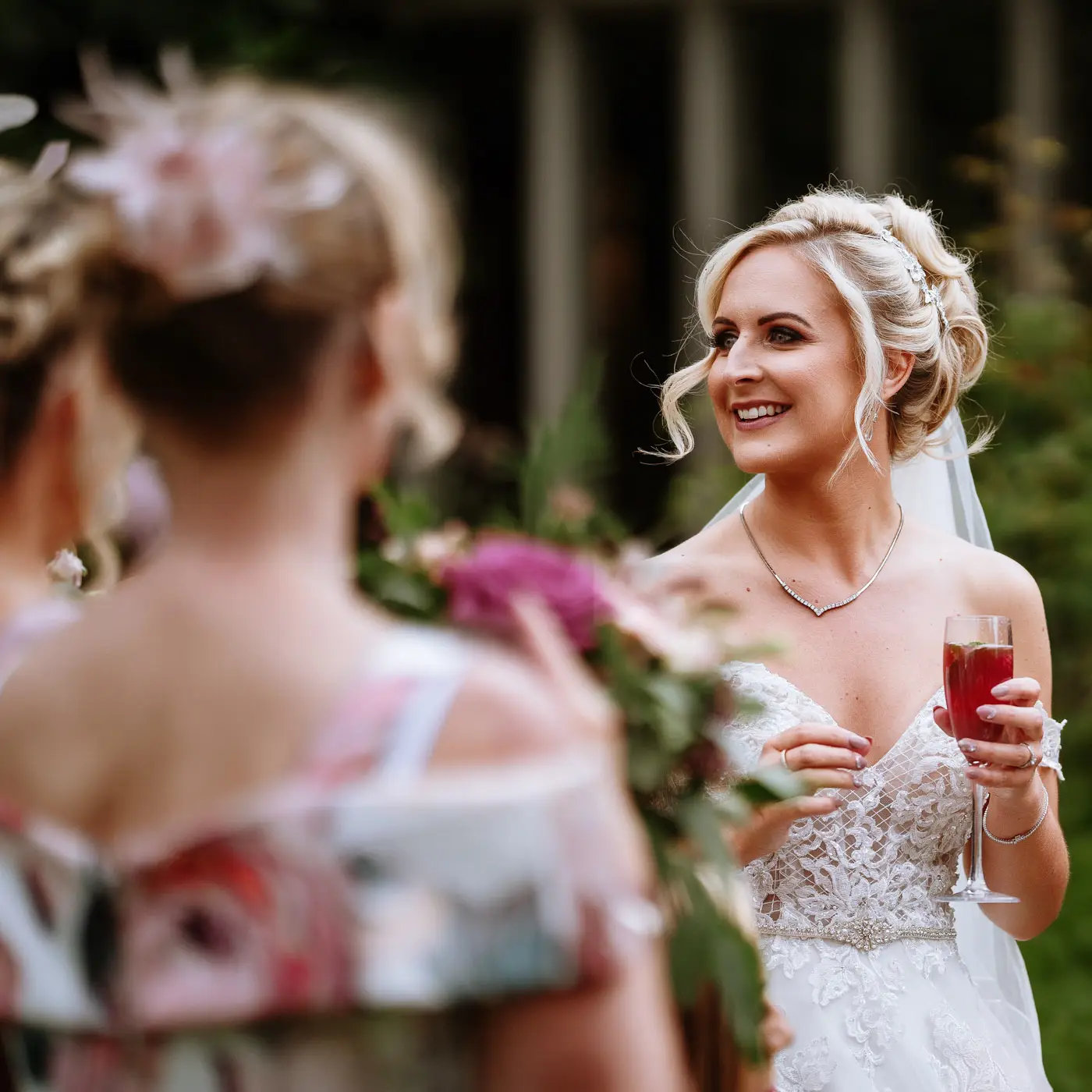 Bride Louise in the coach house gardens at Doddington Hall with her friends and a big smile during her wedding reception in Lincolnshire